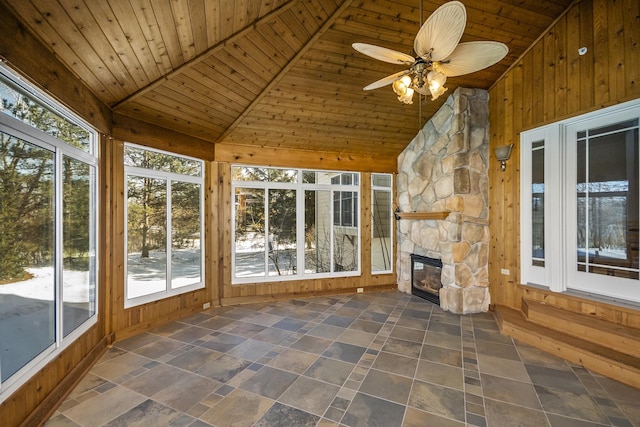 unfurnished sunroom with vaulted ceiling, wooden ceiling, a fireplace, and ceiling fan