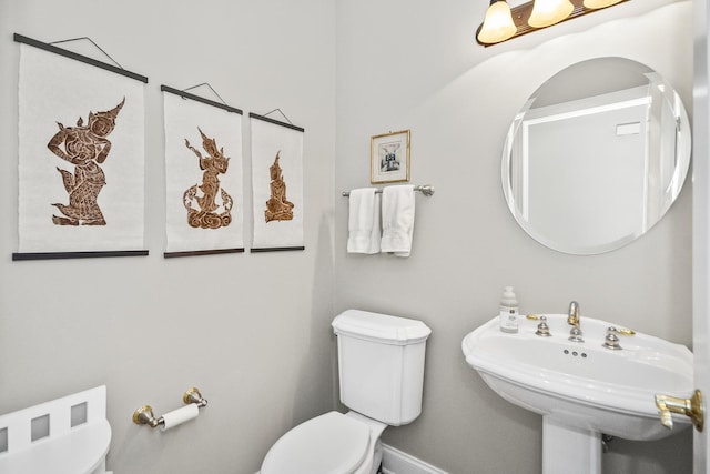 bathroom featuring baseboards, a sink, and toilet