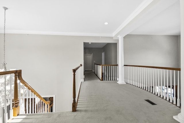 hallway featuring visible vents, crown molding, an upstairs landing, carpet floors, and ornate columns