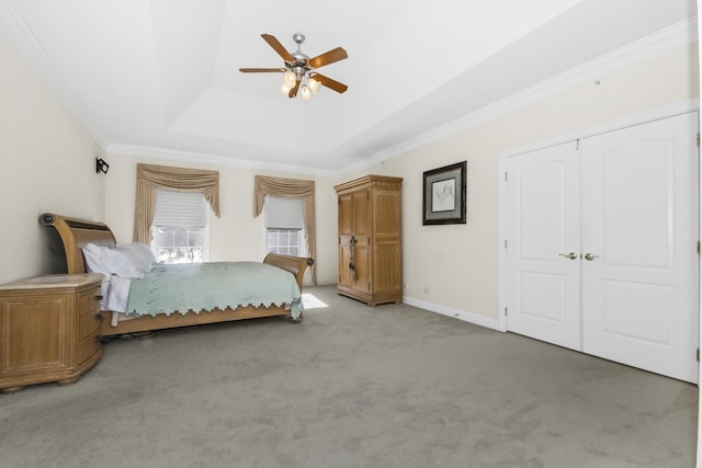 unfurnished bedroom featuring baseboards, a raised ceiling, ceiling fan, carpet, and crown molding