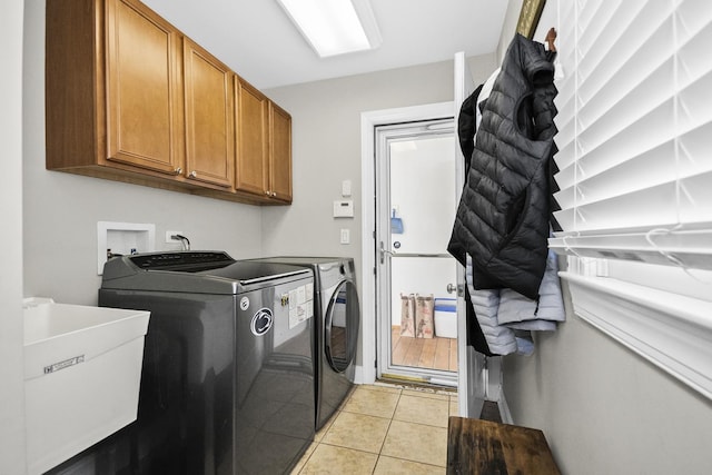 clothes washing area featuring a sink, cabinet space, light tile patterned floors, and washer and dryer