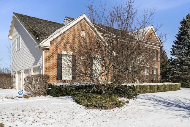 snow covered property with brick siding