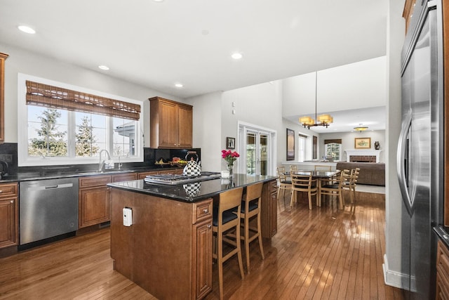 kitchen featuring plenty of natural light, brown cabinets, a center island, stainless steel appliances, and a sink