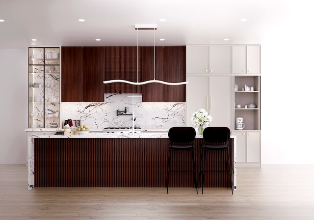 kitchen with pendant lighting, backsplash, light wood-style floors, an island with sink, and modern cabinets