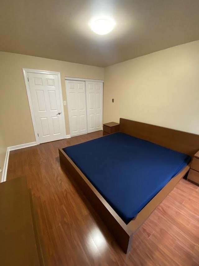 unfurnished bedroom with a closet, wood finished floors, and baseboards