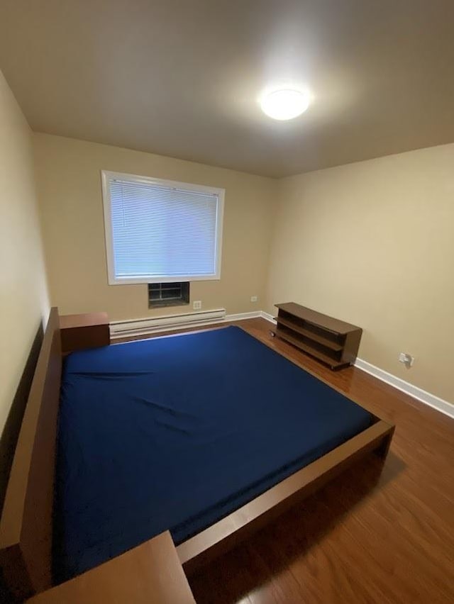 exercise room with baseboards, baseboard heating, and dark wood-type flooring