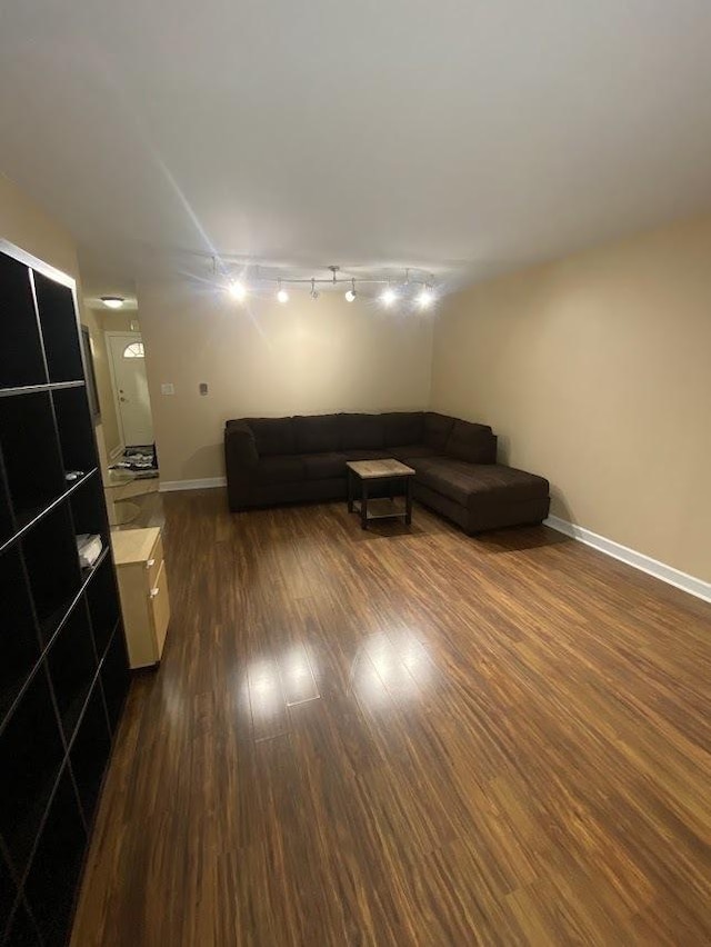 living room with dark wood finished floors, baseboards, and stairs