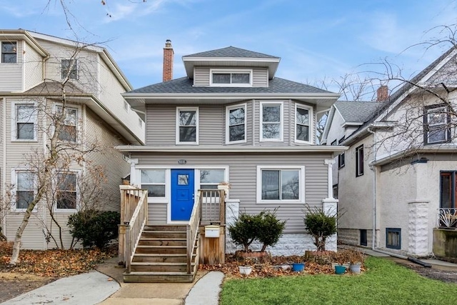 american foursquare style home featuring roof with shingles and a chimney