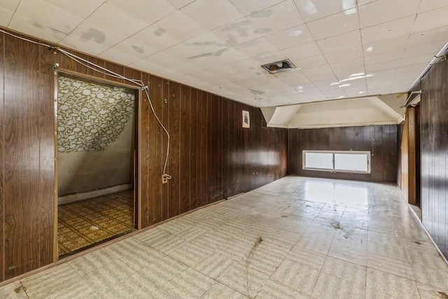 unfurnished room with wood walls, visible vents, and tile patterned floors