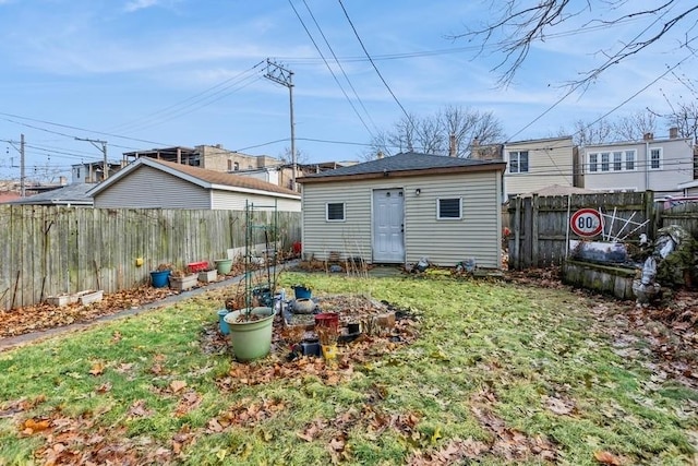 rear view of property featuring a fenced backyard, a yard, and an outdoor structure