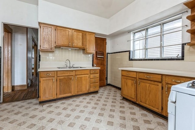 kitchen featuring brown cabinets, open shelves, light countertops, a sink, and range