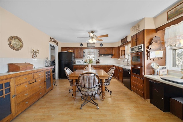 kitchen featuring light wood finished floors, light countertops, black appliances, a ceiling fan, and a sink