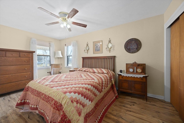 bedroom featuring baseboards, wood finished floors, a closet, and ceiling fan