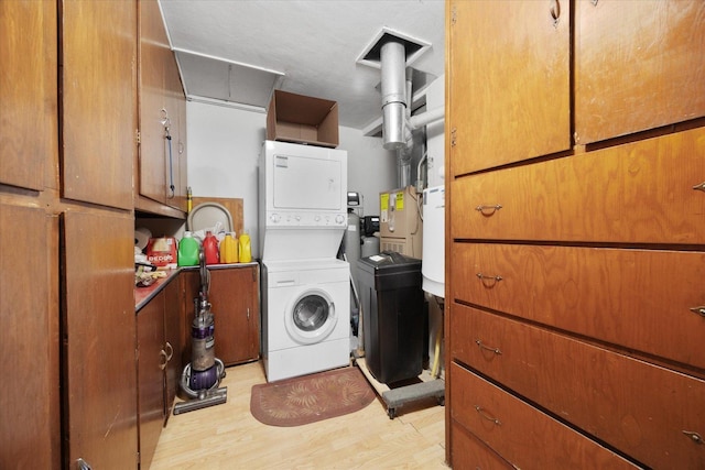 laundry area featuring cabinet space, stacked washer / drying machine, and light wood-type flooring