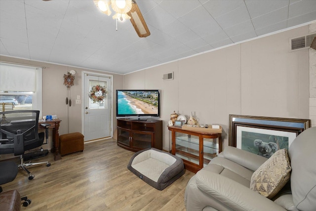 living area with visible vents, ornamental molding, and wood finished floors