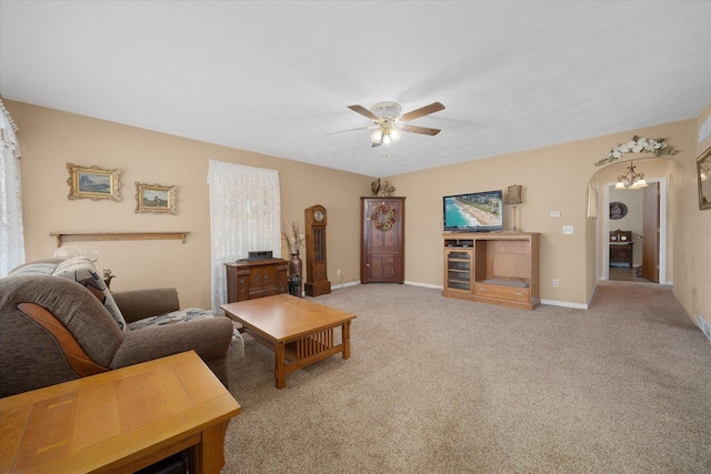 living room with baseboards, arched walkways, light carpet, and a ceiling fan