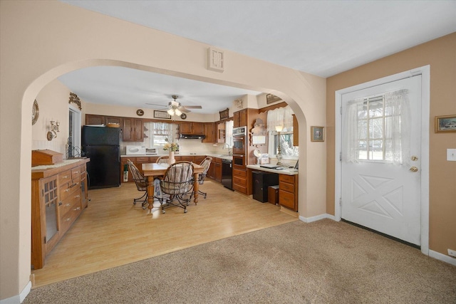 dining room featuring visible vents, light carpet, a ceiling fan, arched walkways, and baseboards