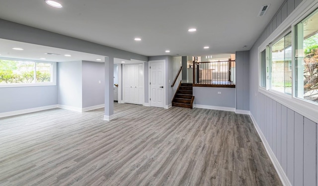 below grade area with stairs, recessed lighting, wood finished floors, and baseboards