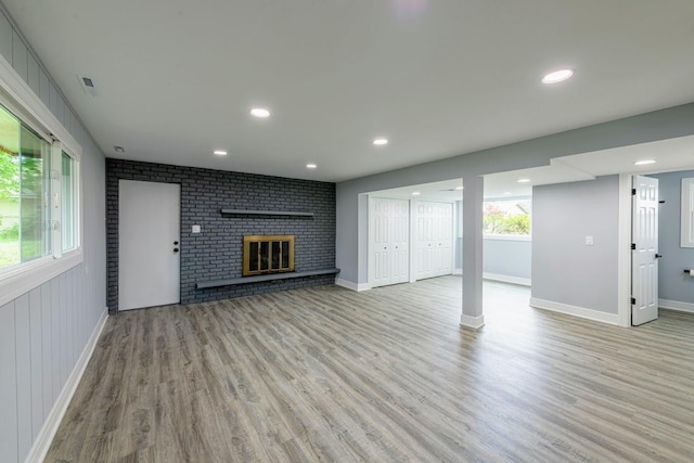 unfurnished living room with light wood-style floors, recessed lighting, a brick fireplace, and baseboards