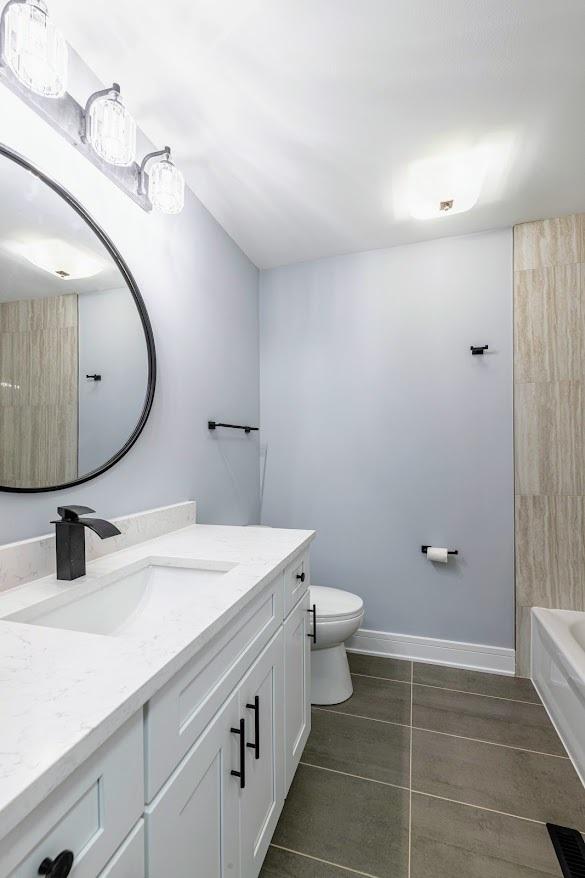 full bathroom with washtub / shower combination, baseboards, vanity, and toilet