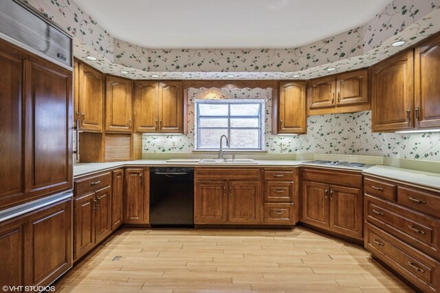 kitchen with stainless steel gas cooktop, a sink, light wood-style floors, black dishwasher, and light countertops