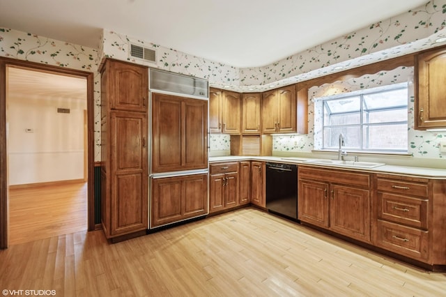 kitchen featuring light countertops, brown cabinetry, a sink, dishwasher, and wallpapered walls