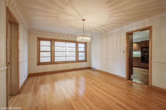 spare room with crown molding, baseboards, a chandelier, and light wood-style floors