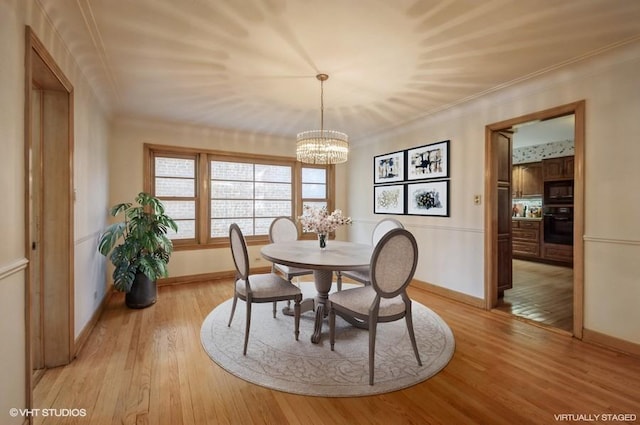 dining area featuring ornamental molding, light wood-type flooring, a notable chandelier, and baseboards