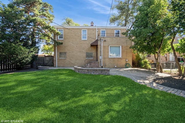 back of house featuring brick siding, a lawn, and fence private yard