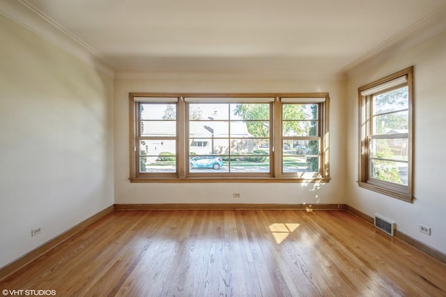 empty room with baseboards, light wood-style flooring, visible vents, and crown molding