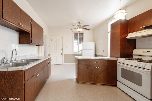 kitchen with light countertops, white appliances, a sink, and under cabinet range hood