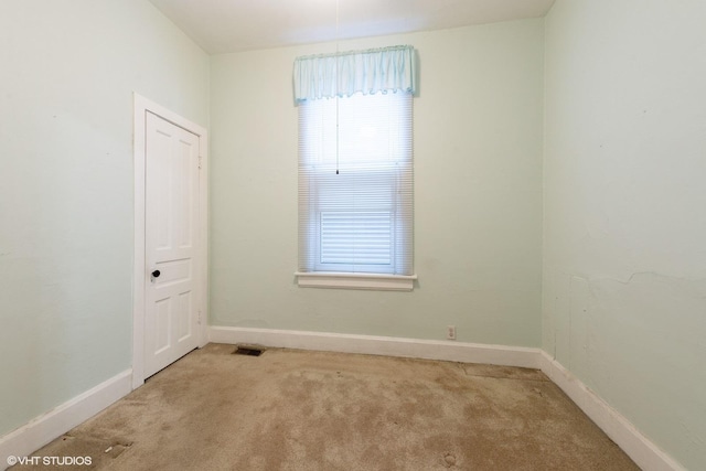 empty room featuring light carpet, visible vents, and baseboards