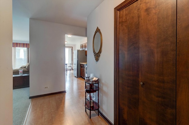 corridor featuring light wood-type flooring and baseboards