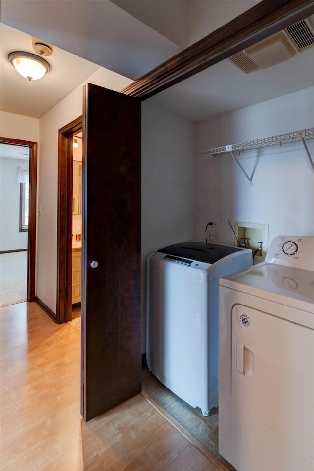 laundry room featuring laundry area, baseboards, light wood finished floors, and washing machine and clothes dryer