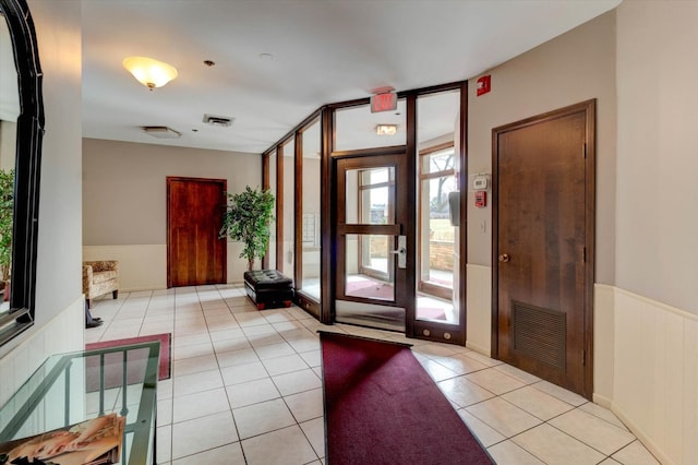 foyer entrance featuring wainscoting, visible vents, floor to ceiling windows, and light tile patterned floors