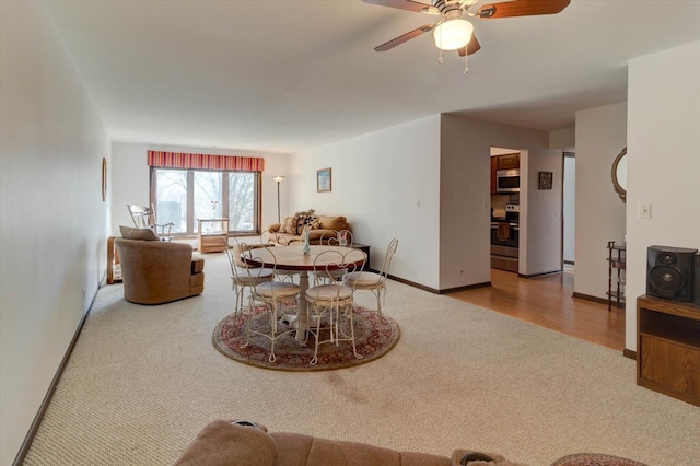 carpeted dining area with ceiling fan and baseboards