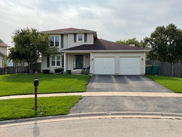 traditional-style house featuring aphalt driveway, a front yard, fence, and a garage