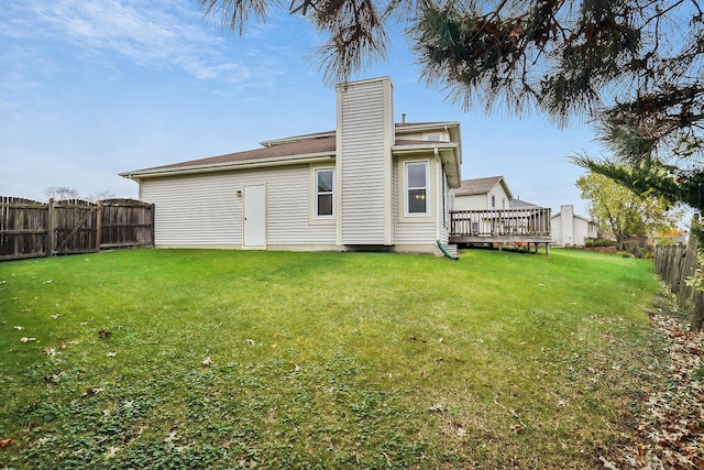 back of house featuring a fenced backyard, a yard, a chimney, and a wooden deck