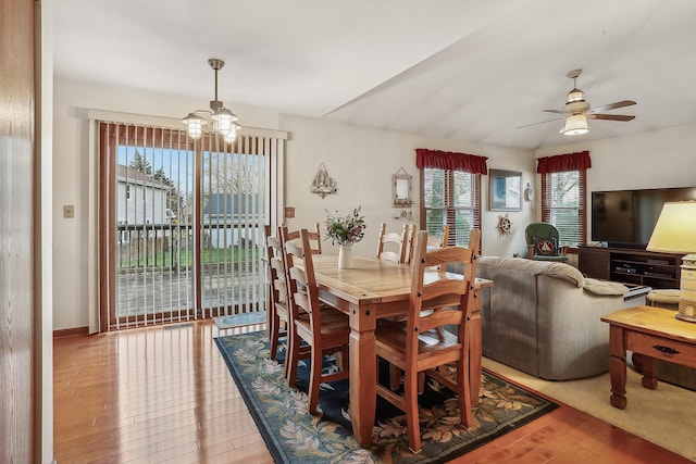 dining space with wood finished floors and ceiling fan with notable chandelier