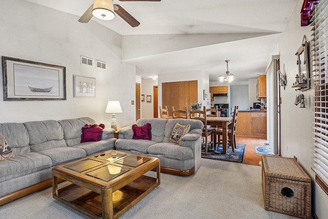 living area featuring lofted ceiling, visible vents, and a ceiling fan