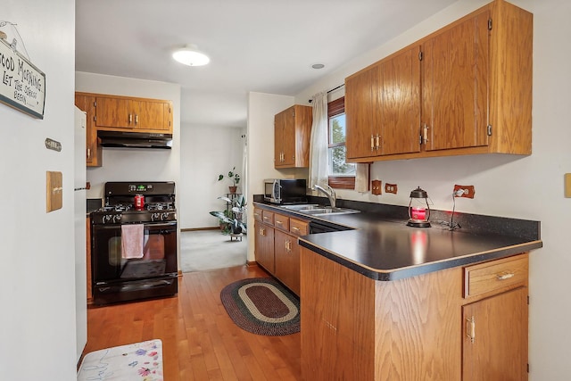 kitchen with black gas stove, dark countertops, stainless steel microwave, and a sink