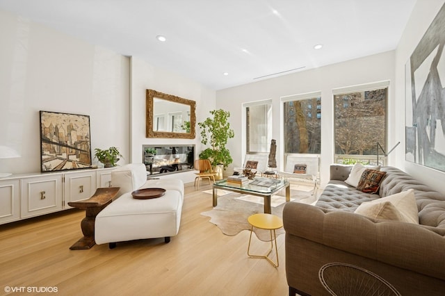 sitting room featuring recessed lighting, light wood-style flooring, and a multi sided fireplace