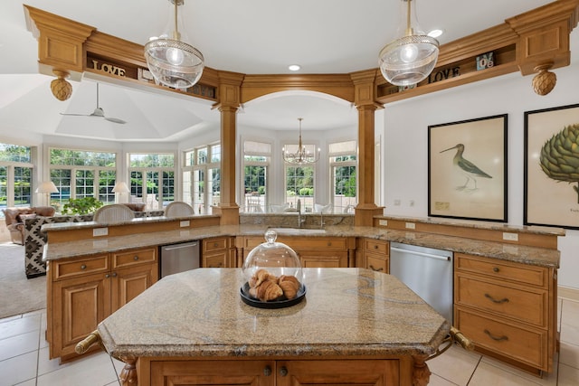 kitchen featuring ornate columns, brown cabinetry, stainless steel dishwasher, and open floor plan