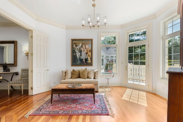 living area with a chandelier, plenty of natural light, light wood-style flooring, and crown molding