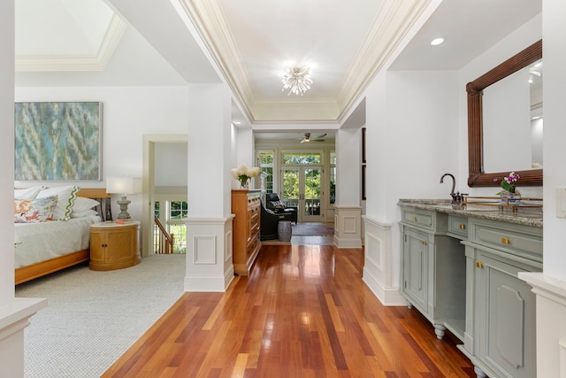 interior space featuring a wainscoted wall, crown molding, decorative columns, light wood finished floors, and a decorative wall