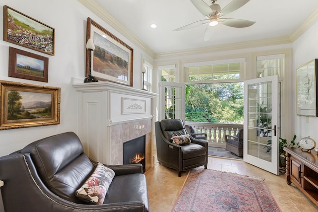 sitting room featuring ceiling fan, a tiled fireplace, and crown molding