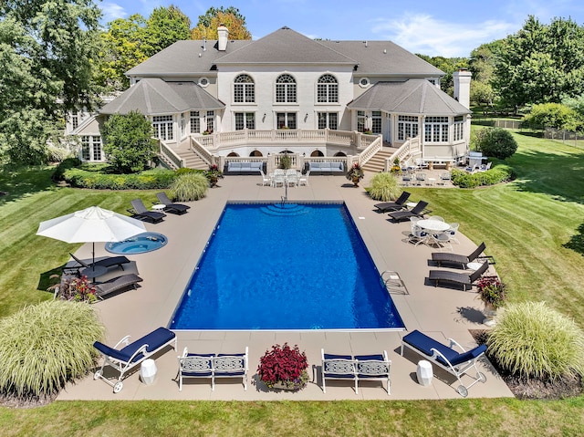 rear view of property featuring a chimney, a lawn, a patio area, an outdoor pool, and a wooden deck