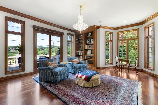 living area featuring ornamental molding, a chandelier, baseboards, and wood finished floors