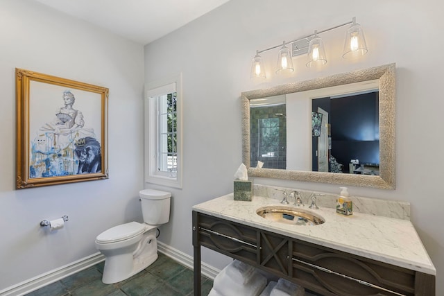 bathroom featuring tile patterned flooring, toilet, vanity, baseboards, and a tile shower