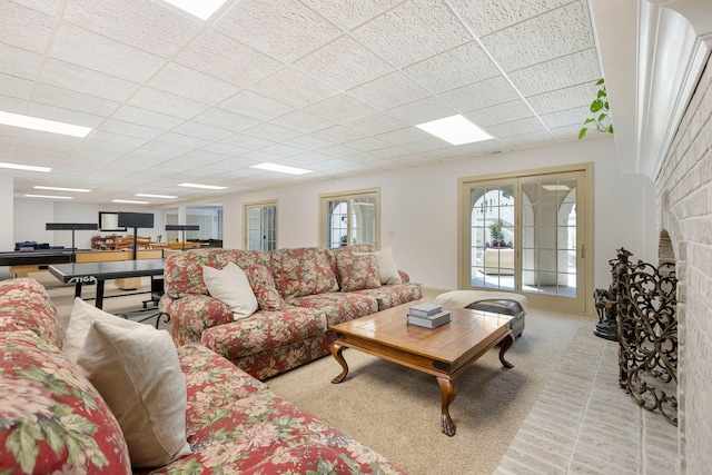 living area featuring a fireplace and a paneled ceiling